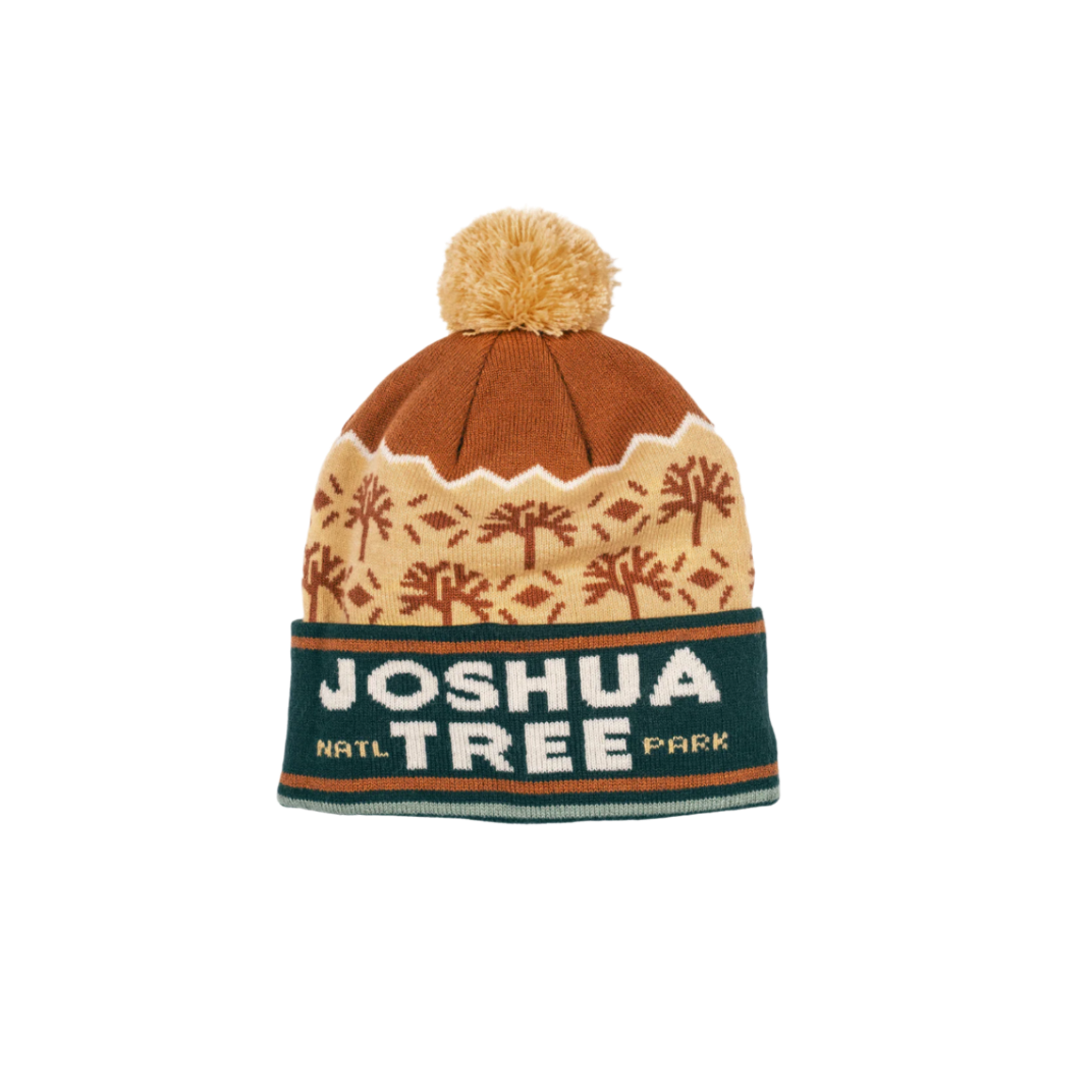 A beanie with a pom-pom on top, featuring geometric patterns and text 'JOSHUA TREE NATL PARK' on the cuff.
