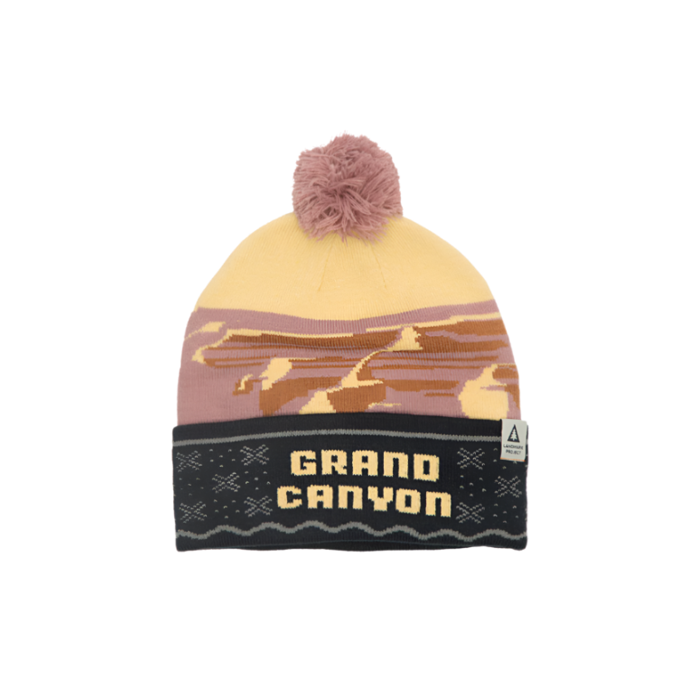 A beanie with a camouflage pattern featuring beige, brown, and black colors, and the text 'GRAND CANYON' displayed prominently on the front.