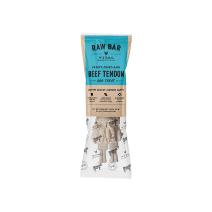 A package of RAW BAR Vital Essentials Freeze-Dried Raw Beef Tendon Dog Treats. The packaging features a teal blue top section with black text, a natural brown kraft paper middle section with product benefits, and a white bottom section showing the freeze-dried beef tendon treats inside.