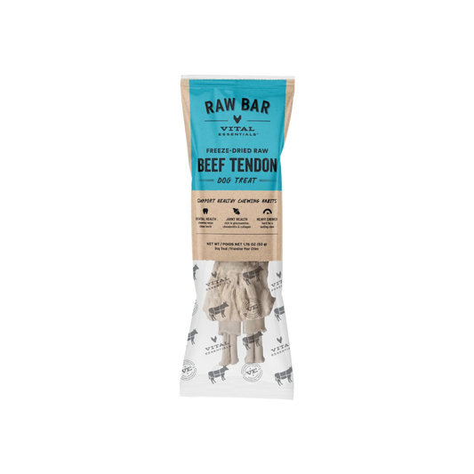 A package of RAW BAR Vital Essentials Freeze-Dried Raw Beef Tendon Dog Treats. The packaging features a teal blue top section with black text, a natural brown kraft paper middle section with product benefits, and a white bottom section showing the freeze-dried beef tendon treats inside.