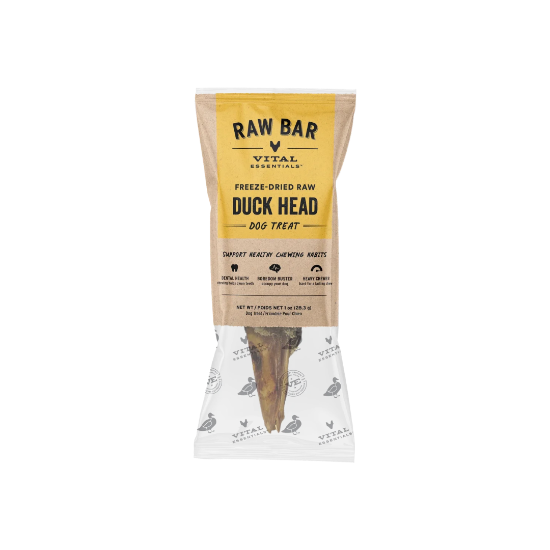 A packaged dog treat from Vital Essentials, specifically Raw Bar Freeze-Dried Raw Duck Head dog treat, shown in a clear bag with a kraft paper label and a visible bone-shaped treat inside.