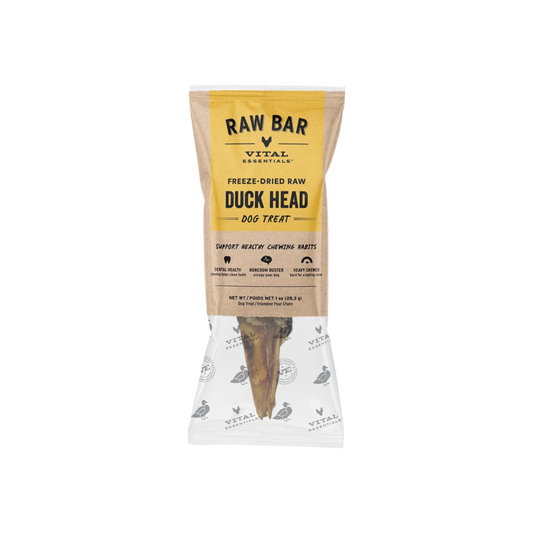 A packaged dog treat from Vital Essentials, specifically Raw Bar Freeze-Dried Raw Duck Head dog treat, shown in a clear bag with a kraft paper label and a visible bone-shaped treat inside.