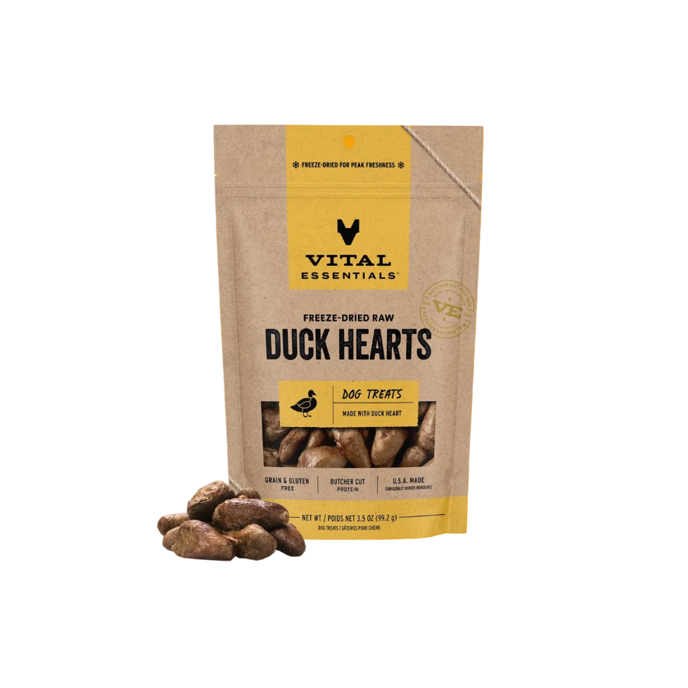 A bag of Vital Essentials Freeze-Dried Raw Duck Hearts dog treats on a solid orange background, with several treats displayed in front of the bag.