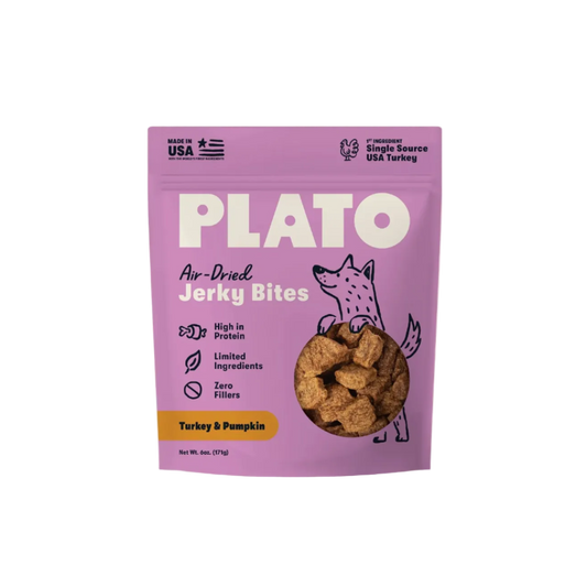 A purple stand-up pouch of Plato Air-Dried Jerky Bites, Turkey & Pumpkin flavor, shown against a light cream background. The packaging features a cartoon dog illustration and a clear window displaying the brown jerky pieces inside.