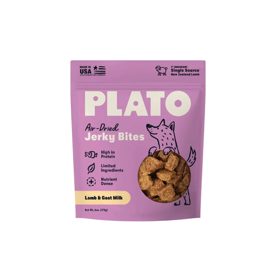 A purple stand-up pouch of Plato Air-Dried Jerky Bites for dogs, featuring a cartoon fox illustration and a circular window showing the brown jerky pieces inside. The packaging highlights 'Lamb & Goat Milk' flavor and includes 'Made in USA' and 'Single Source New Zealand Lamb' claims.