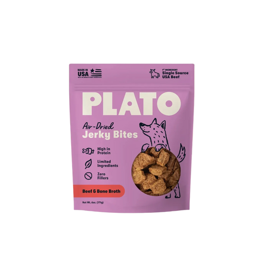 A package of Plato Air-Dried Jerky Bites for Beef & Bone Broth, featuring a light purple pouch with white text, a cartoon dog illustration, and a clear window showing the brown jerky inside, set against a solid cream background.