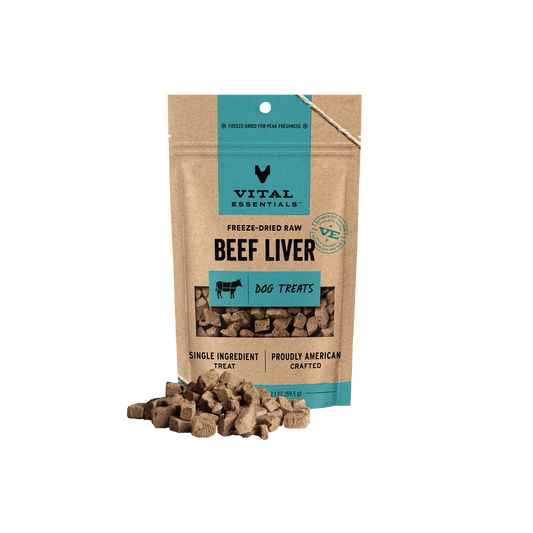 A stand-up pouch of Vital Essentials Beef Liver dog treats on a white background, with several brown cube-shaped treats spilled in front of the package.